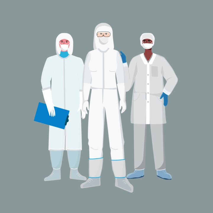 Three cleanroom operators in full-body coveralls standing up.